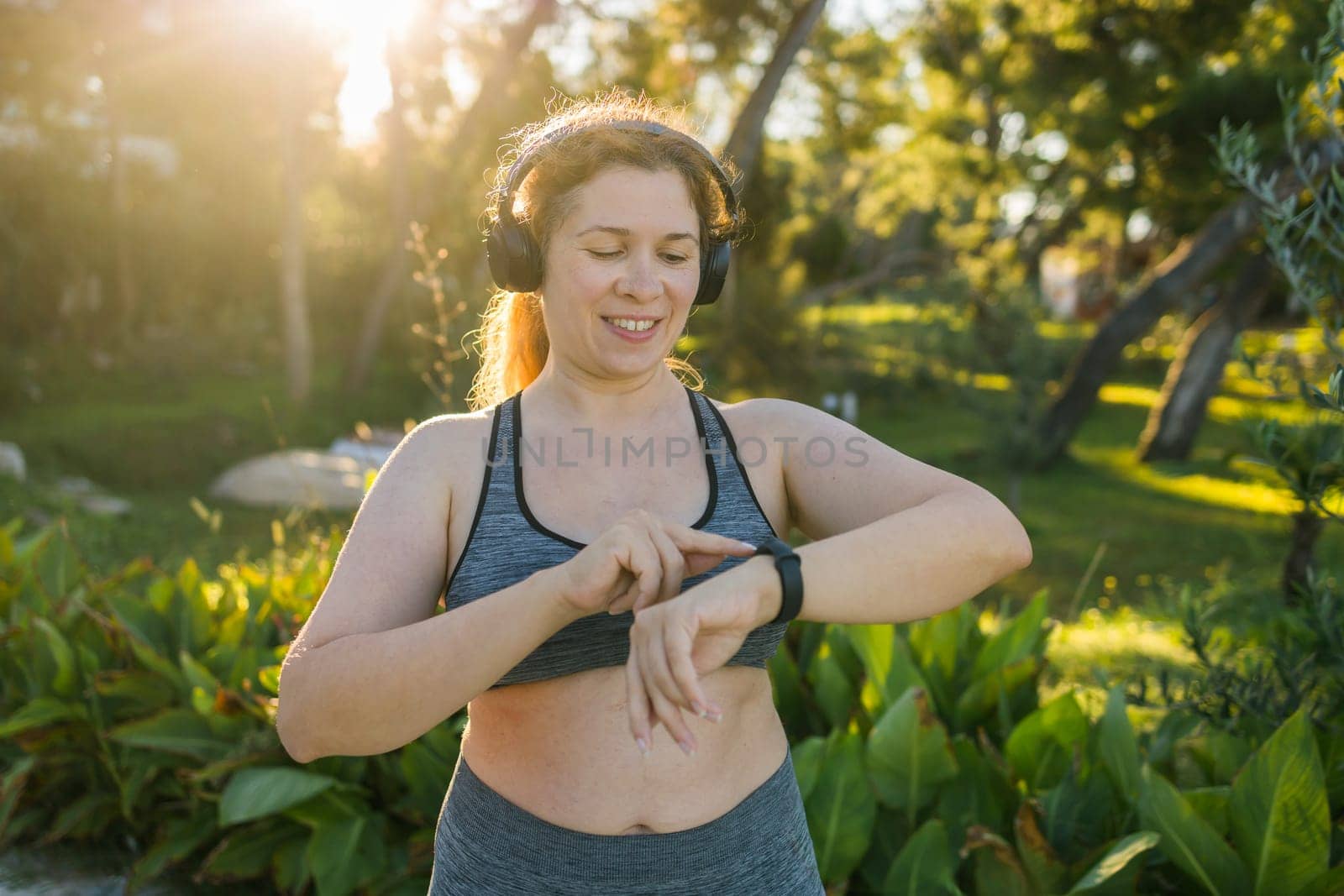 Fat woman checking time or heart rate from smart watch. Exercise or running outdoors for weight loss idea concept. Wellness and wellbeing concept