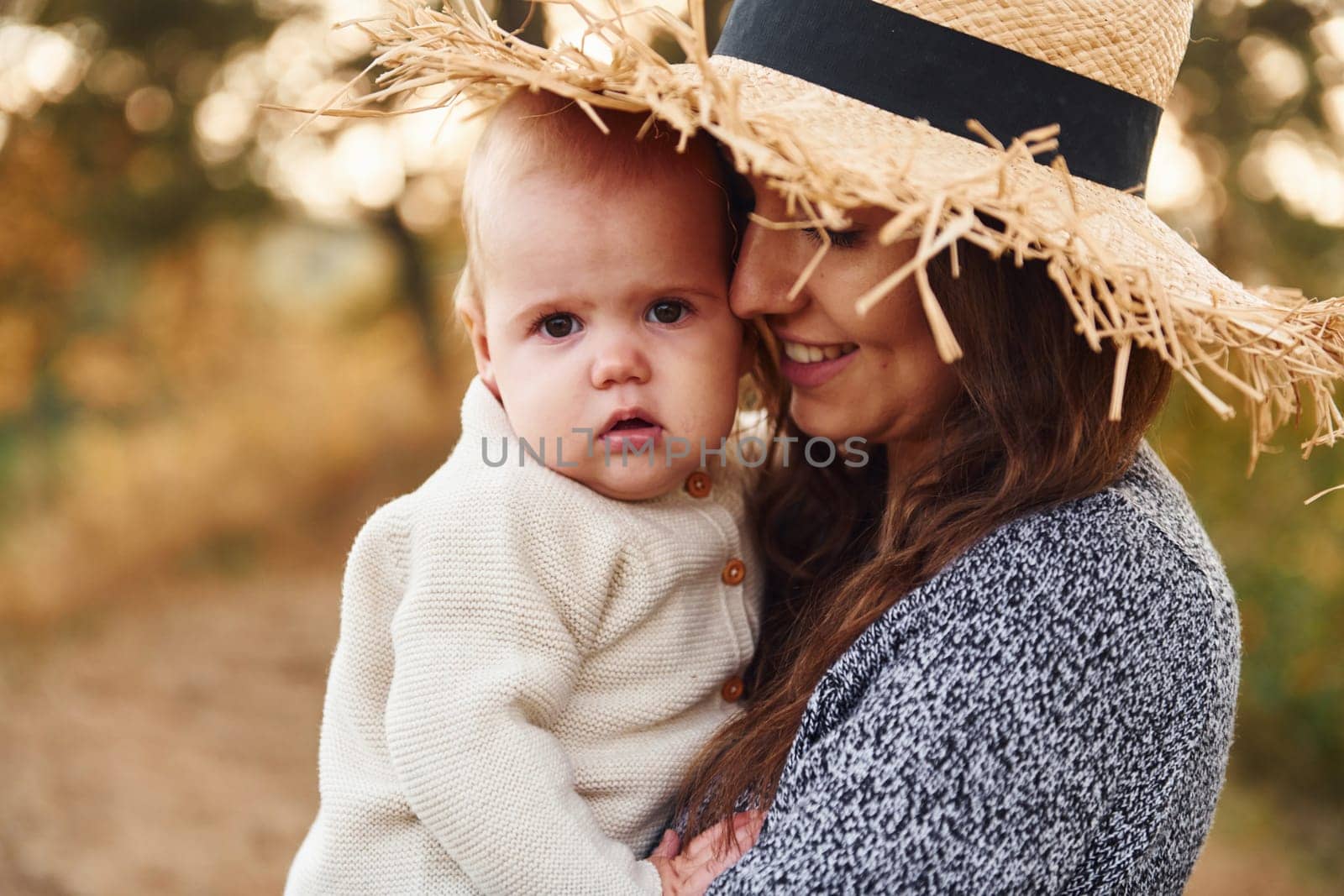 Young mother with her little baby rests outdoors at autumn season.