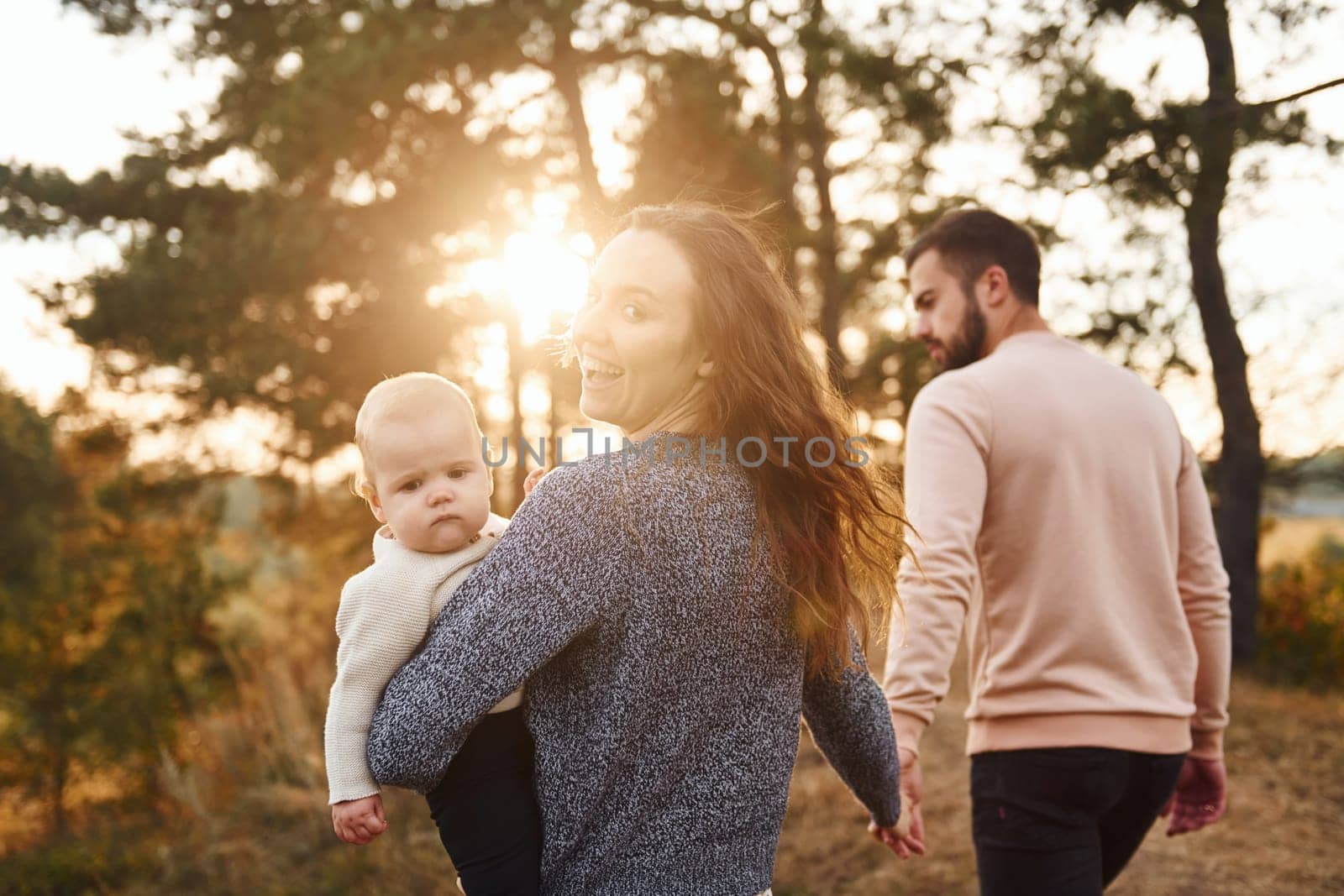 Unity of the people. Happy family of mother, family and little baby rests outdoors. Beautiful sunny autumn nature.