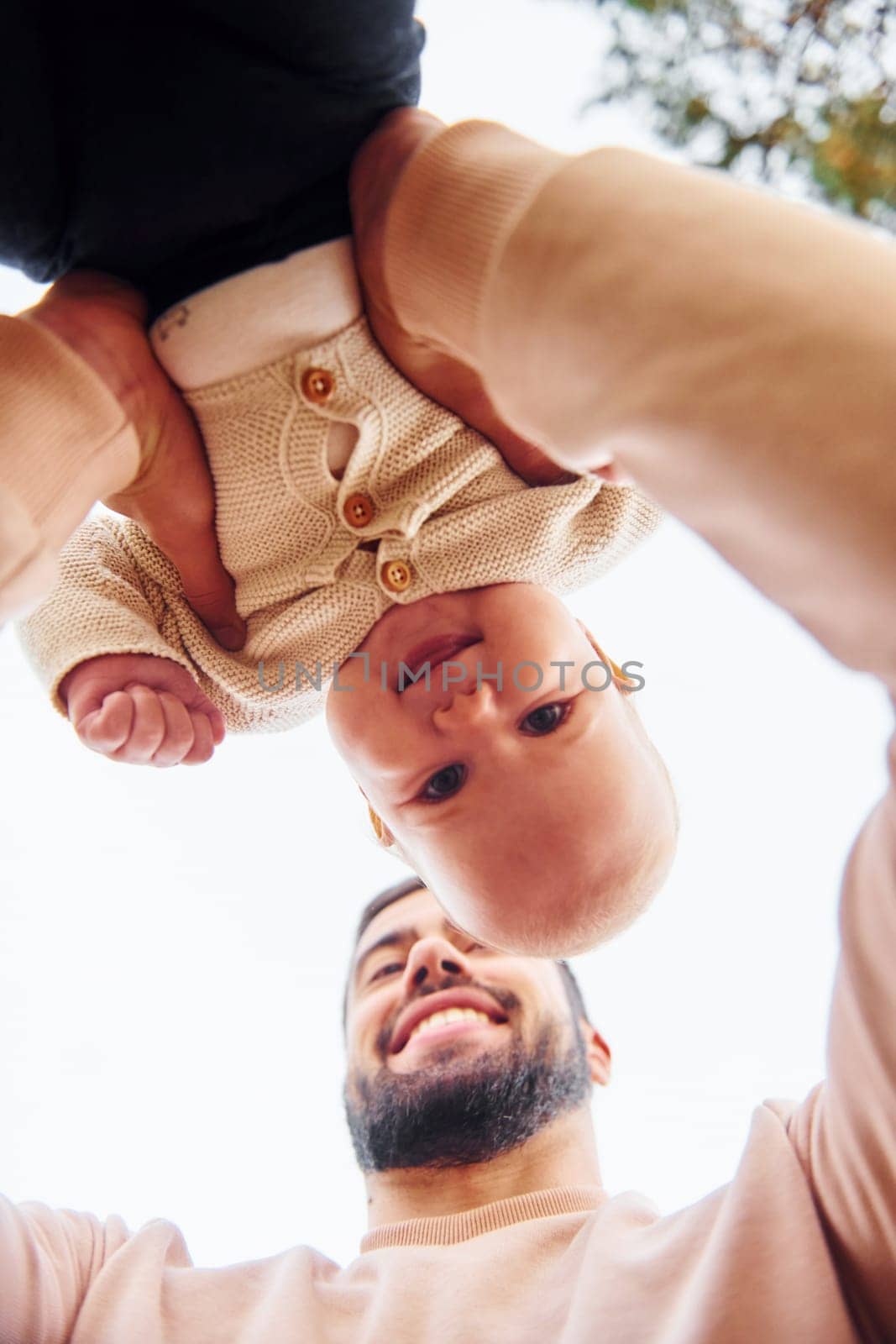 Bearded father playing with his child outdoors at sunny daytime outdoors.