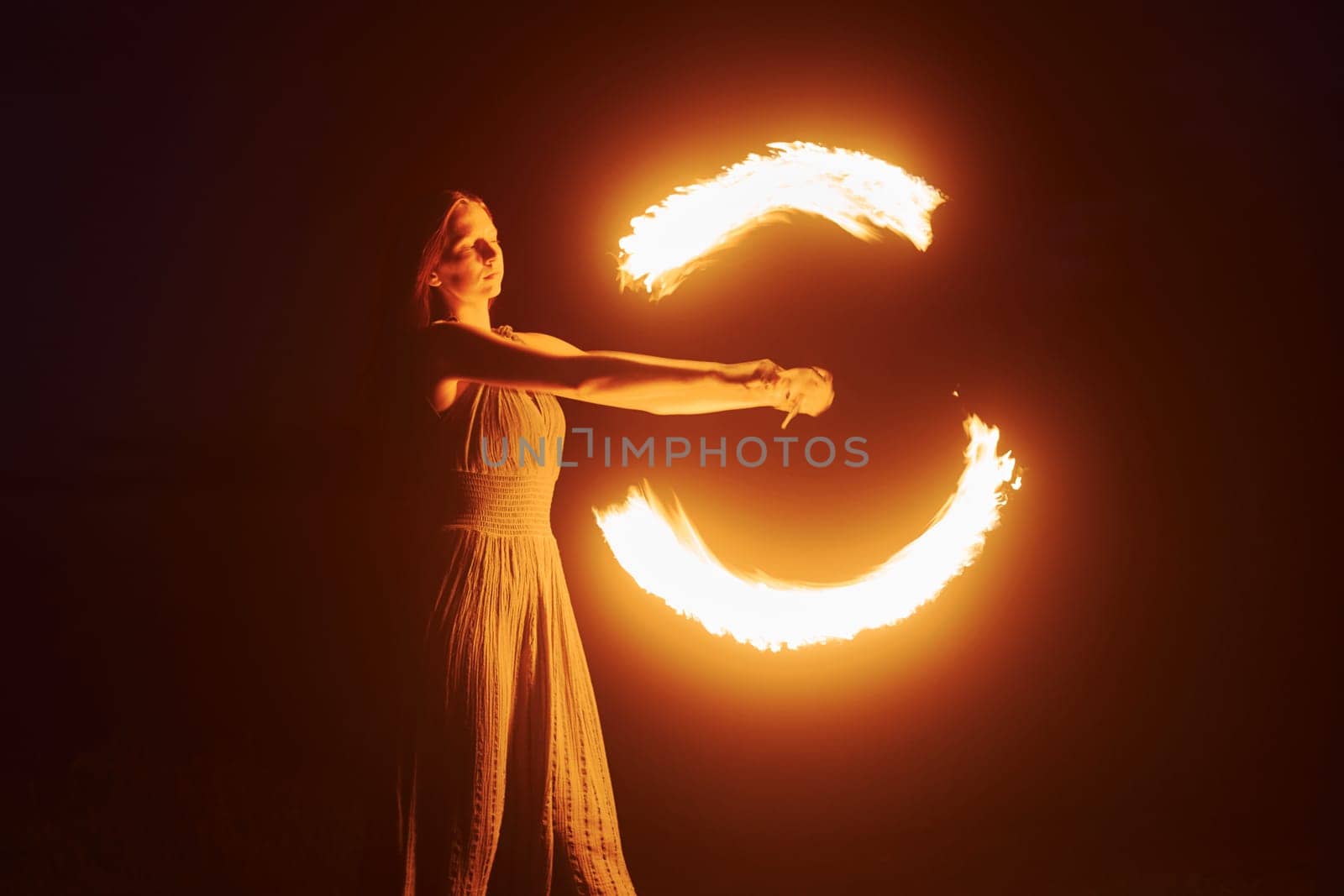 Photo with a long exposure. Fire show by woman in dress in night Carphatian mountains. Beautiful landscape.