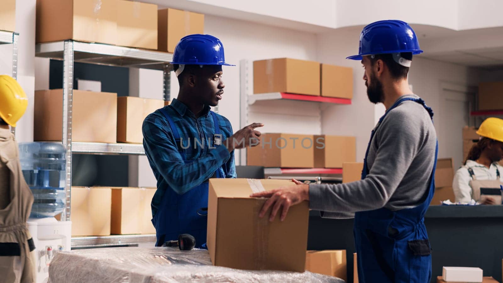 Team of diverse men using scanner and tablet for logistics and inventory, scanning barcodes for merchandise cargo in storage room. Young people in overalls working in stockroom.