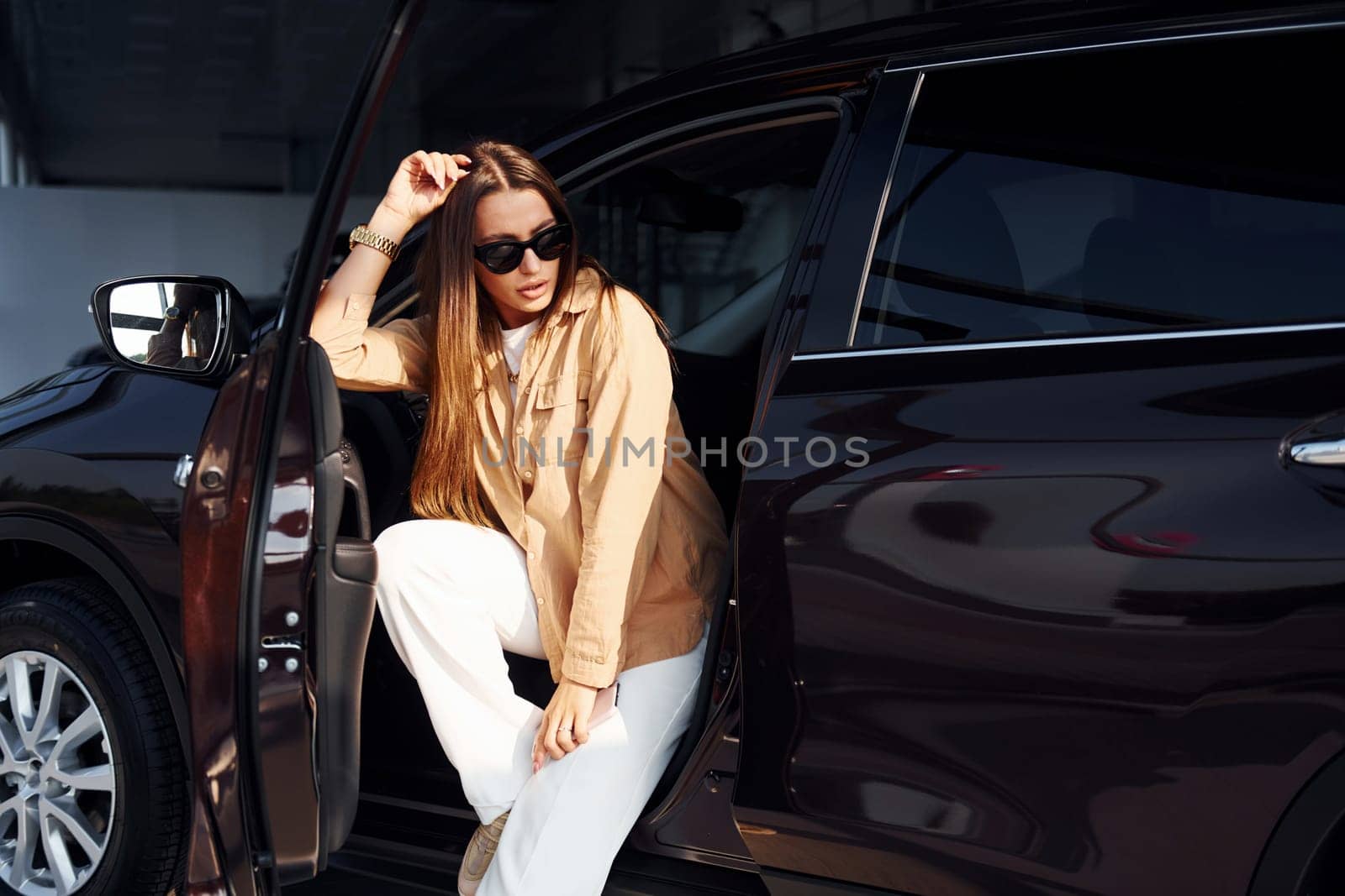 Enjoying fresh air. Fashionable beautiful young woman and her modern automobile.