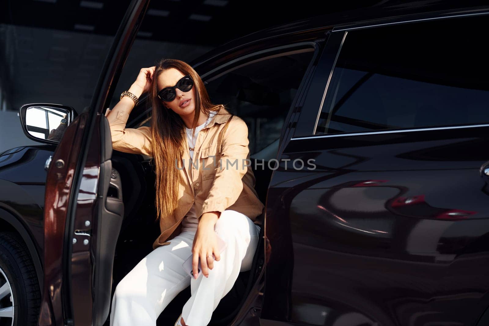 Enjoying fresh air. Fashionable beautiful young woman and her modern automobile.