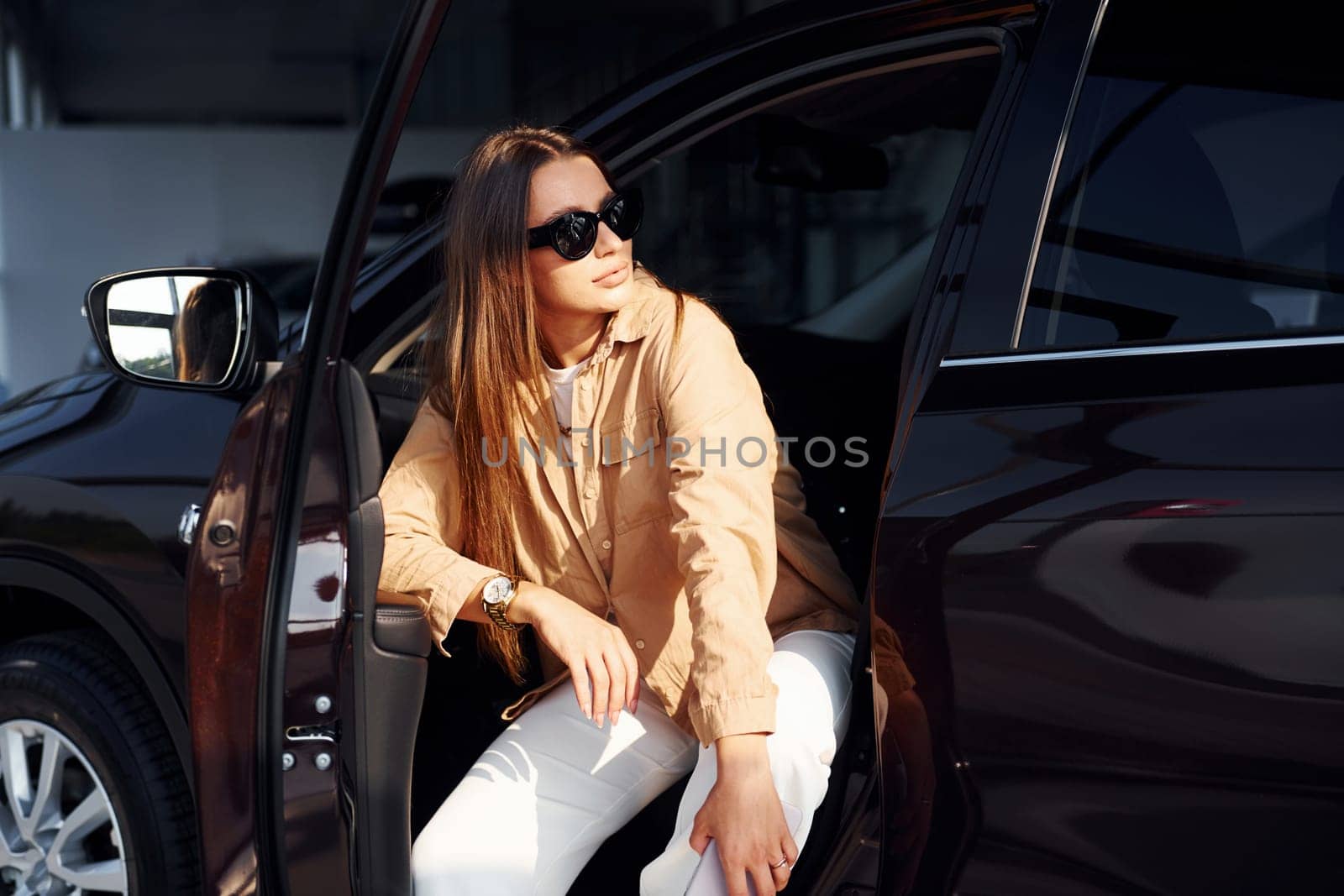 Enjoying fresh air. Fashionable beautiful young woman and her modern automobile.