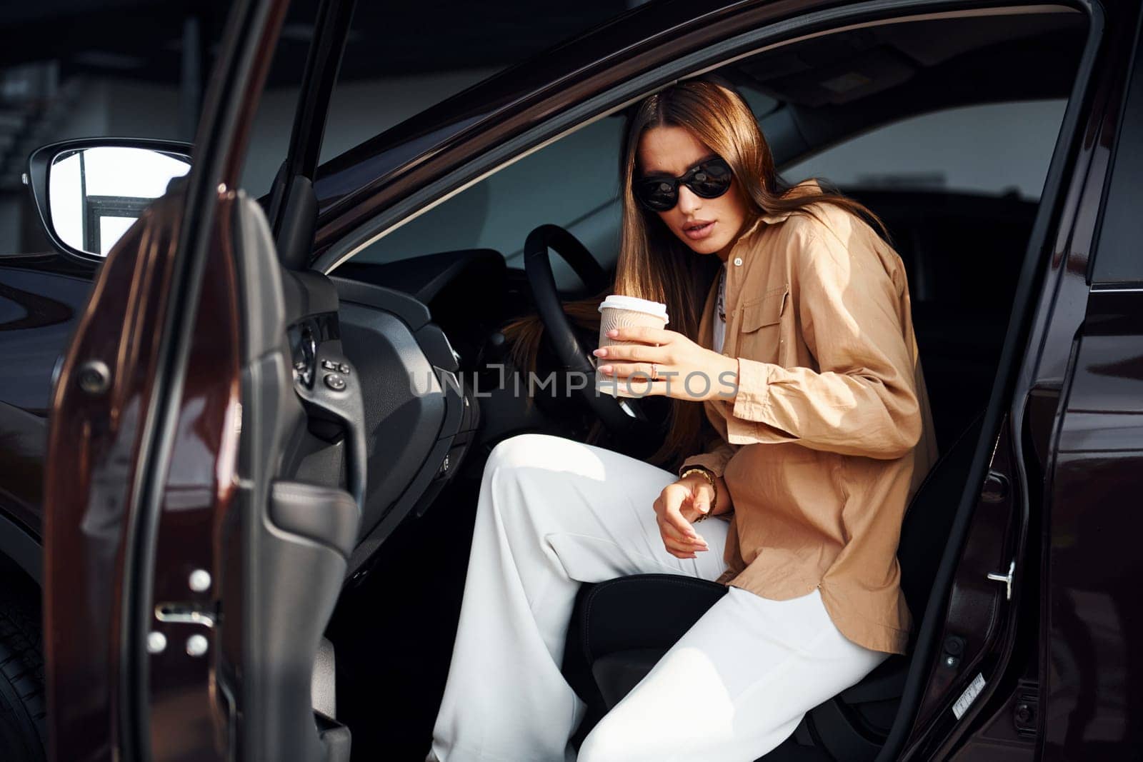 Coffee break. Fashionable beautiful young woman and her modern automobile.