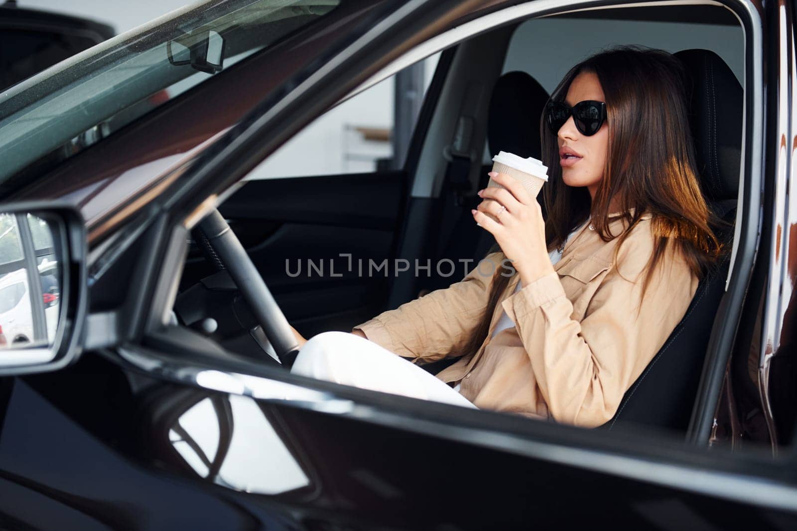 Coffee break. Fashionable beautiful young woman and her modern automobile.