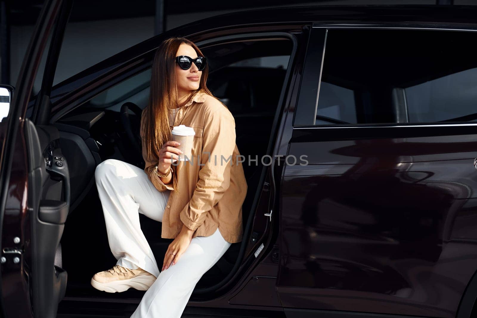 Coffee break. Fashionable beautiful young woman and her modern automobile.