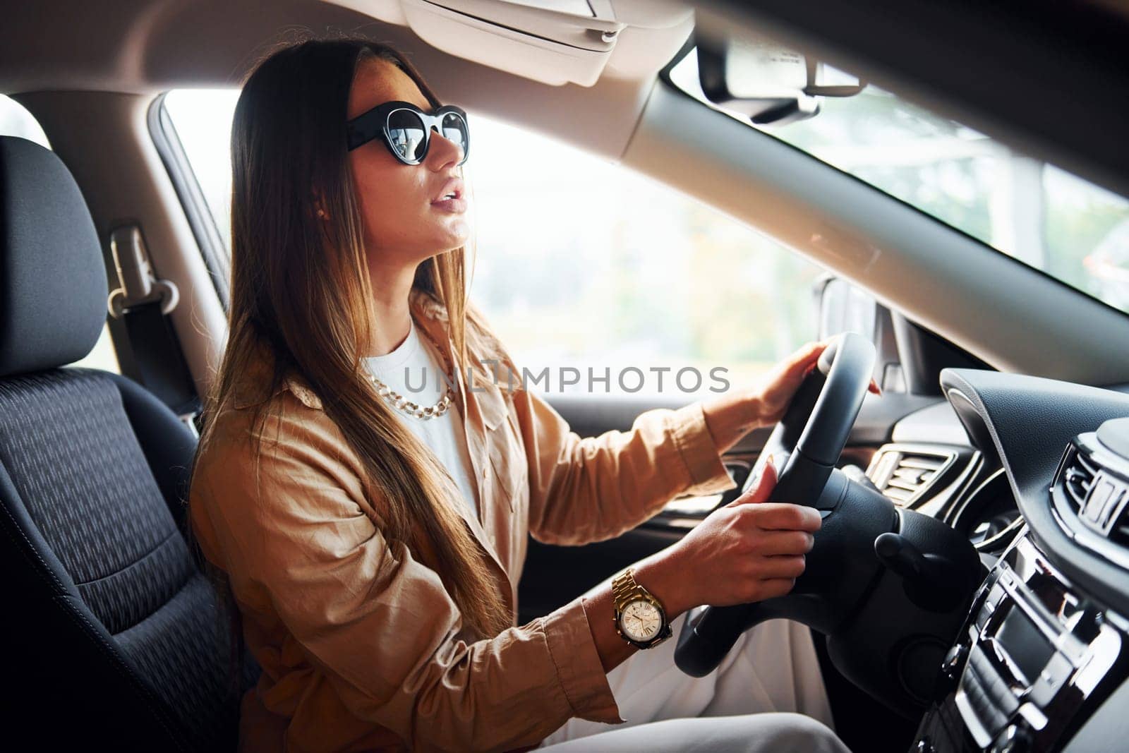 Side view of fashionable beautiful young woman that is inside her modern automobile.