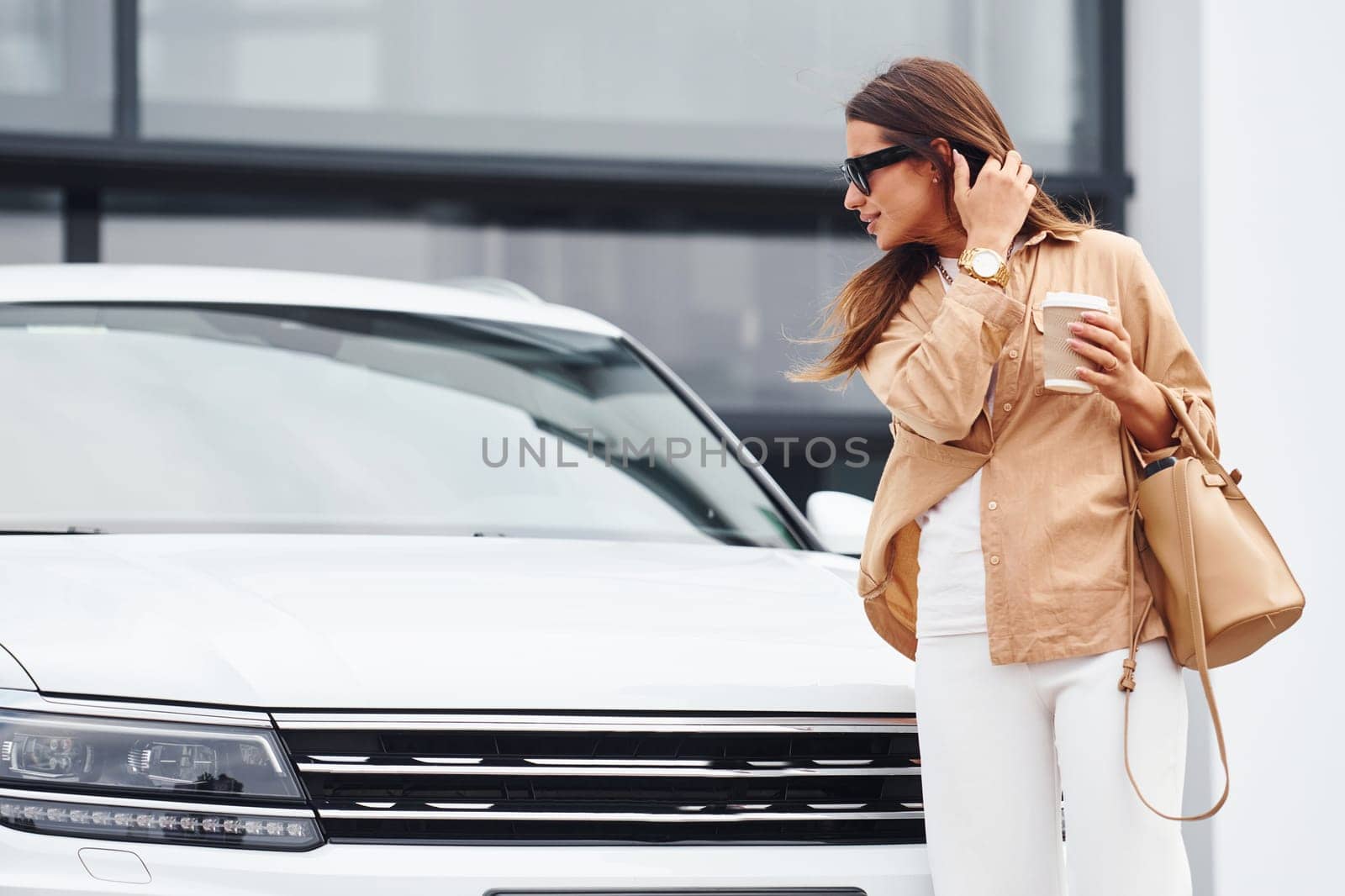 Outside near car. Fashionable beautiful young woman and her modern automobile.