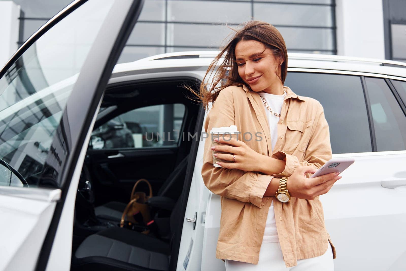 With coffee and phone. Fashionable beautiful young woman and her modern automobile by Standret