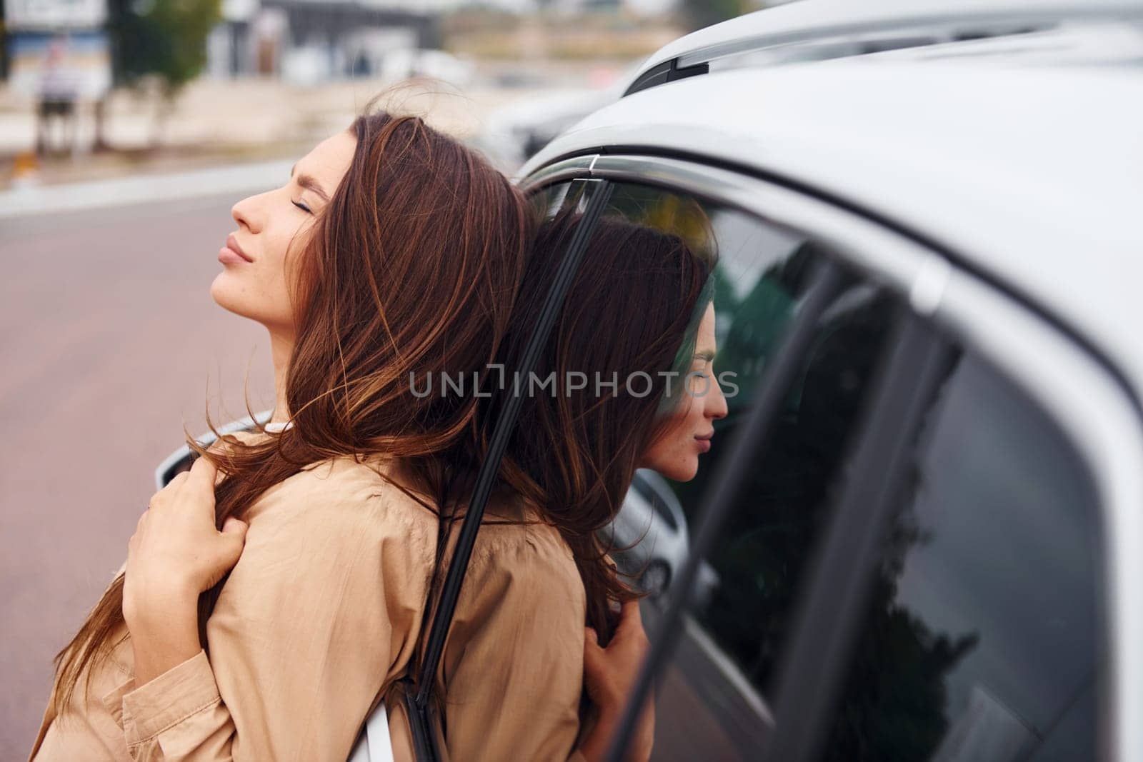 Leans on the door. Fashionable beautiful young woman and her modern automobile.