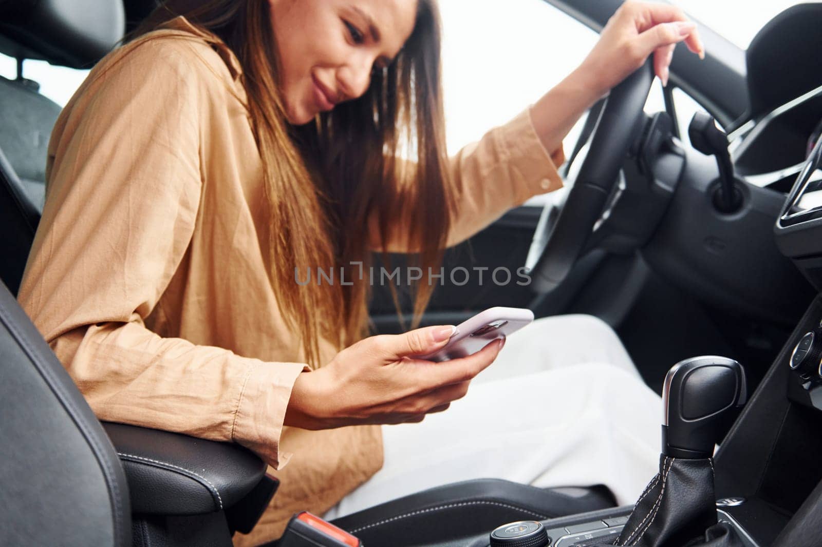 Side view of fashionable beautiful young woman that is inside her modern automobile by Standret