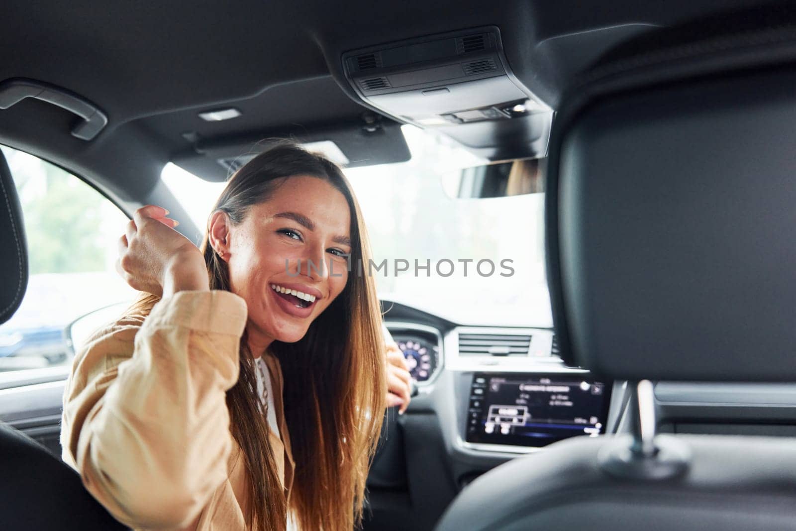 Driver looks back and smiling. Fashionable beautiful young woman and her modern automobile by Standret