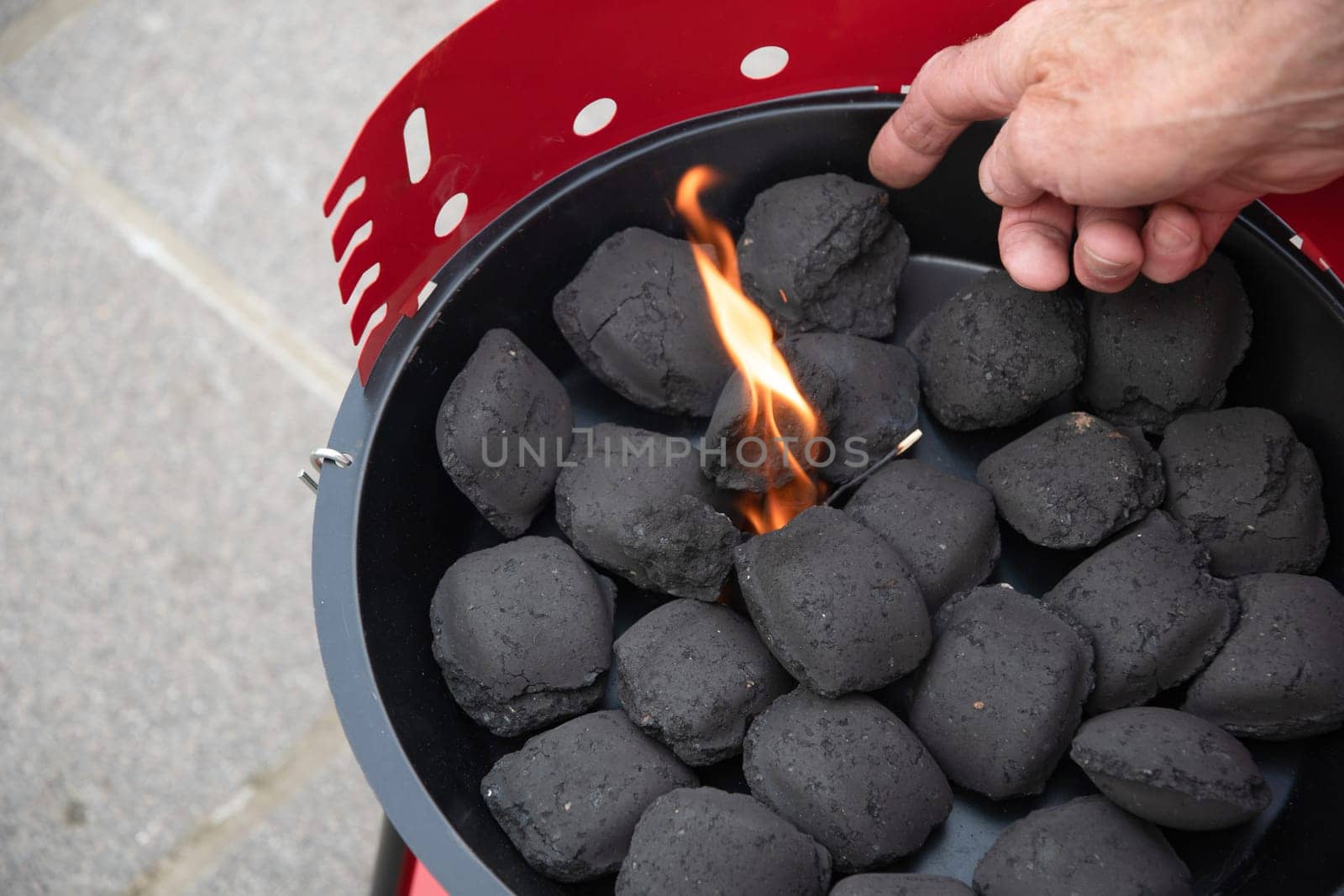 a man lights a fire with a lighter special charcoals for a barbecue a barbecue house on the terrace prepares a place for a barbecue. High quality photo