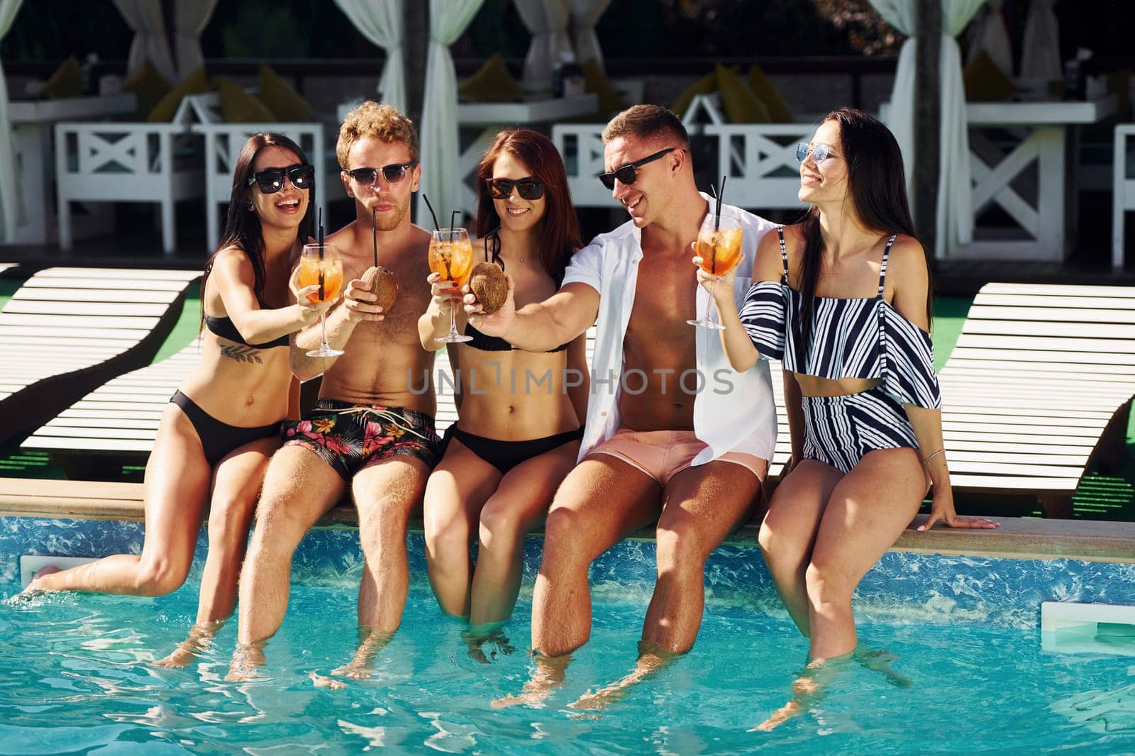 Group of young happy people have fun in swimming pool at daytime.
