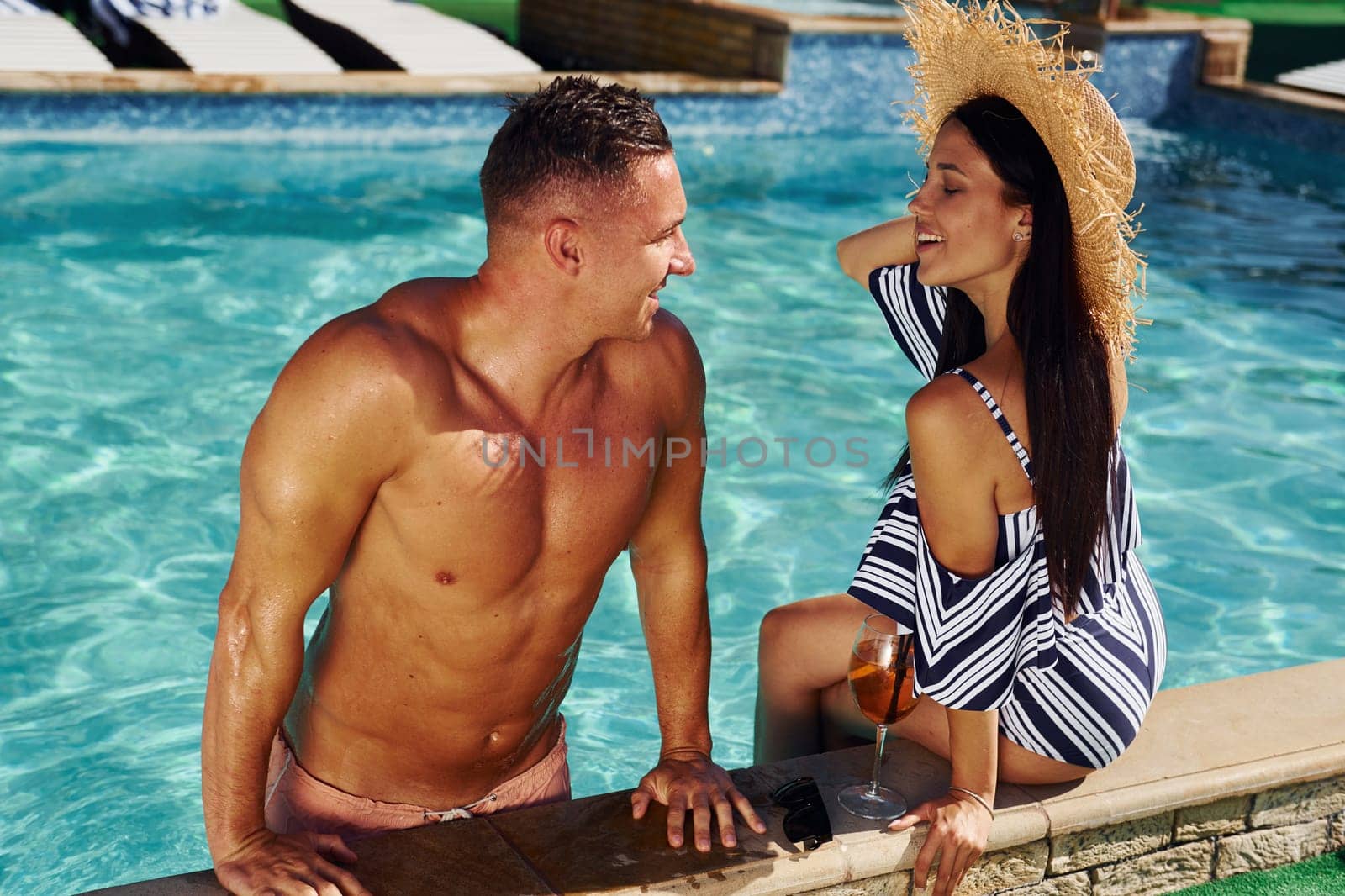 Cheerful couple or friends together in swimming pool at vacation by Standret