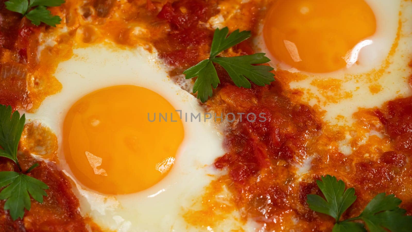 Two egg shakshuka in tomato sauce with fresh tomatoes, spices and herbs. Close-up scrambled eggs.