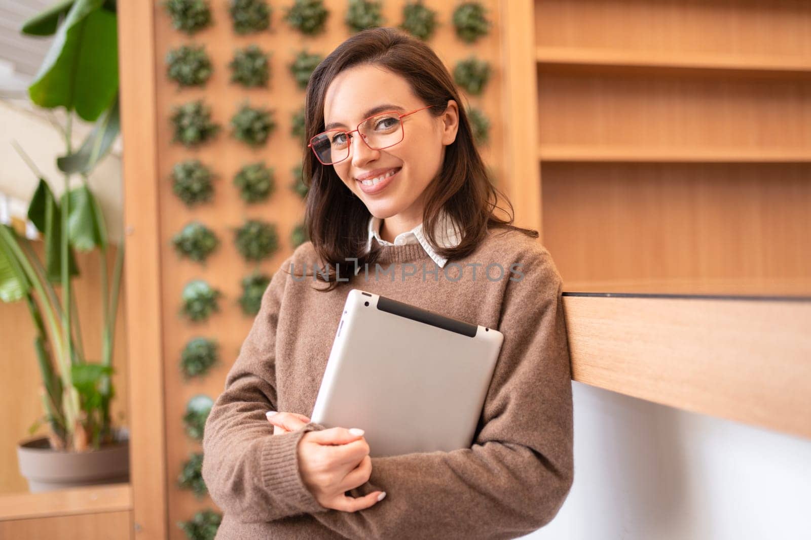 Woman student with tablet computer standing smile and looking camera. Female person studying or working online on touch pad. Modern technologies and communication.