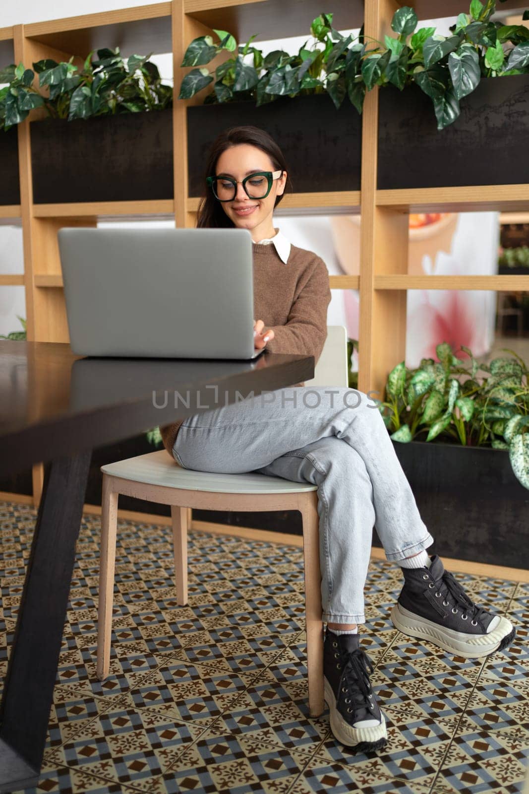 Woman Wearing Glasses using Laptop. Charming businesswoman in eyeglasses and casual clothes working with laptop computer watching screen. Elegant business female full length vertical shoot