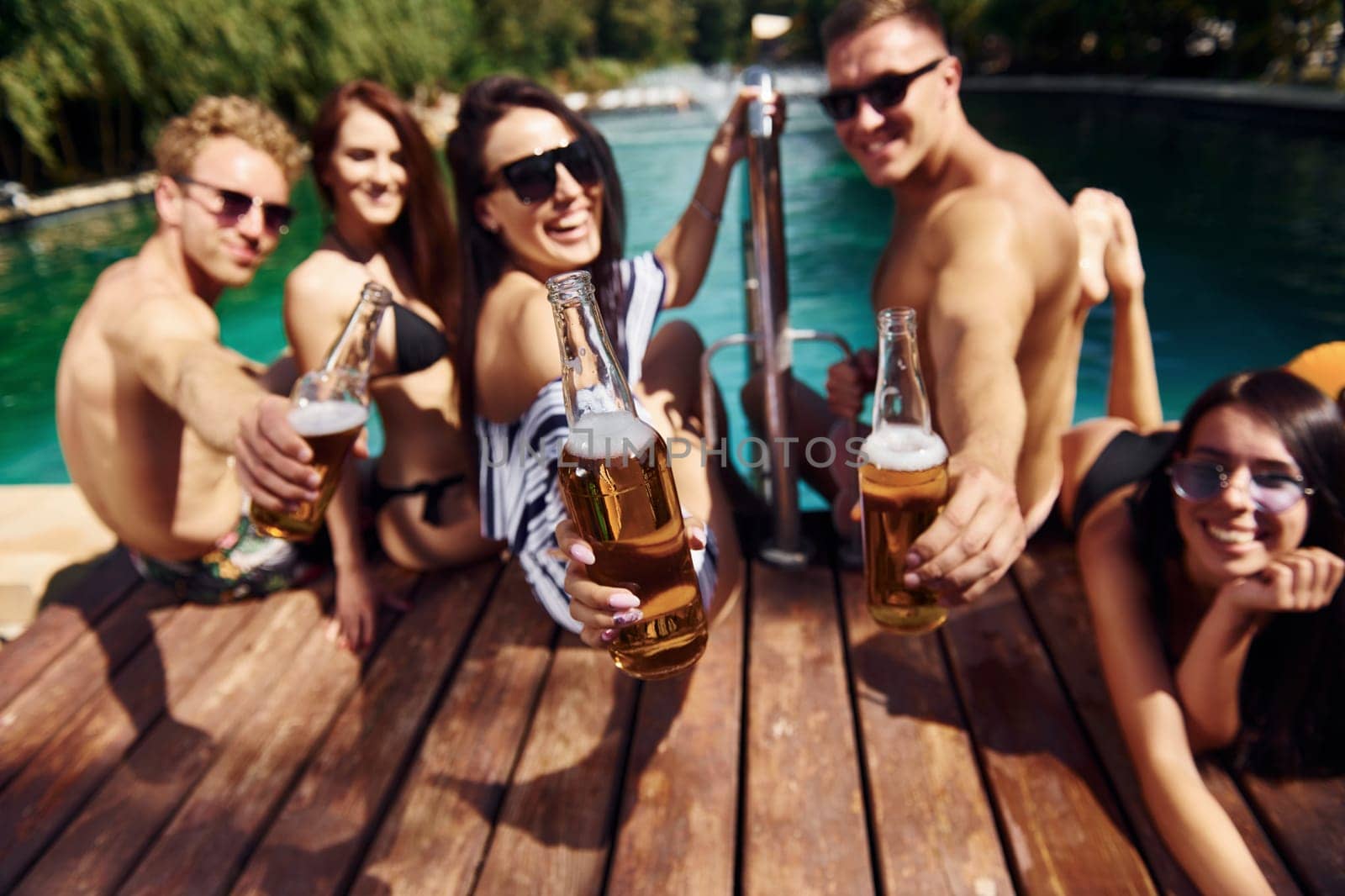 Taking a rest together. Group of young happy people have fun in swimming pool at daytime.