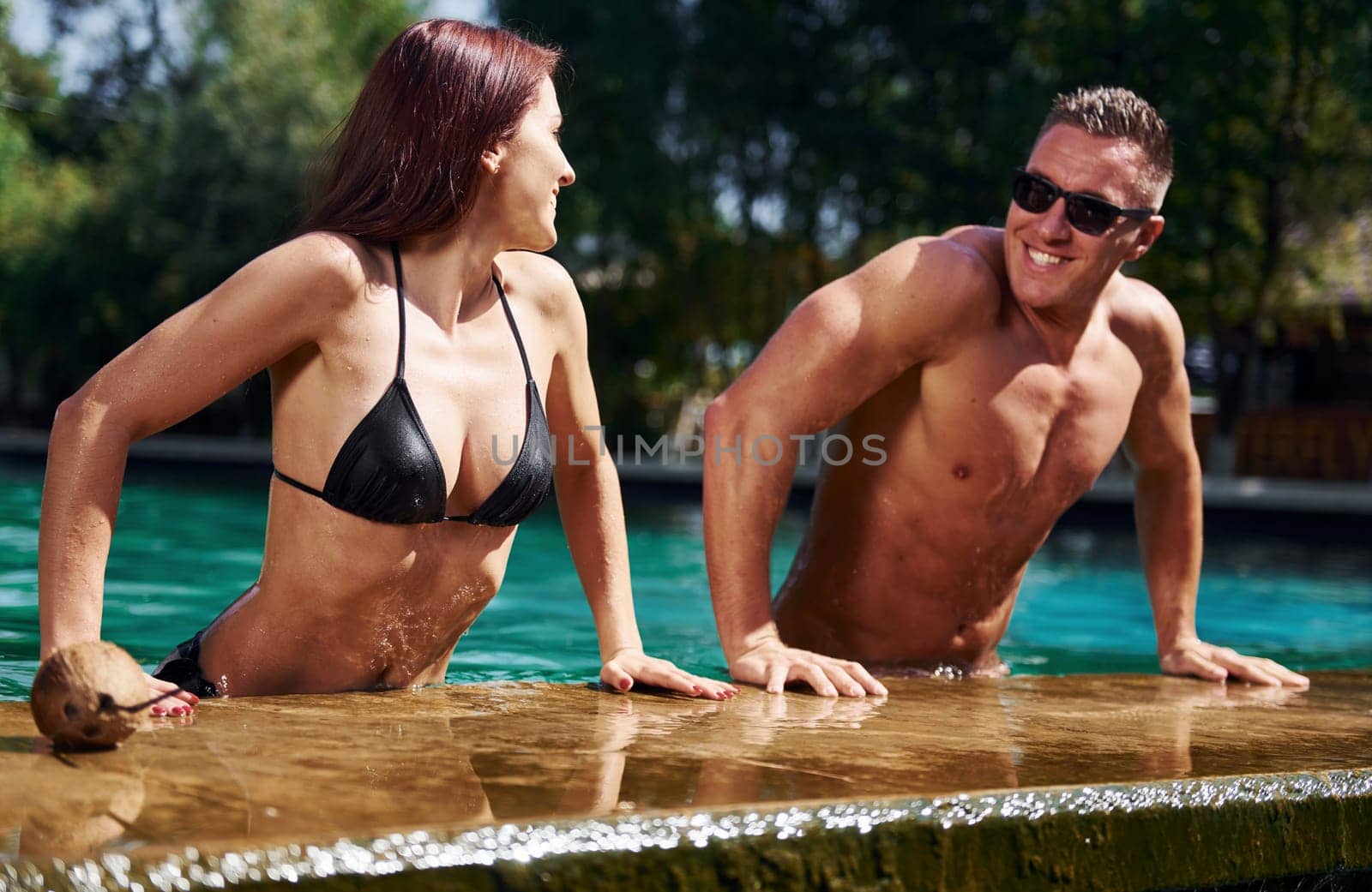 Positive people. Cheerful couple or friends together in swimming pool at vacation by Standret