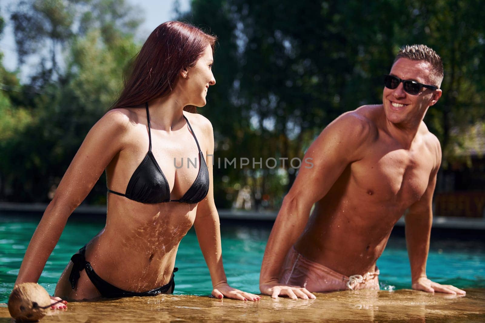 Positive people. Cheerful couple or friends together in swimming pool at vacation by Standret