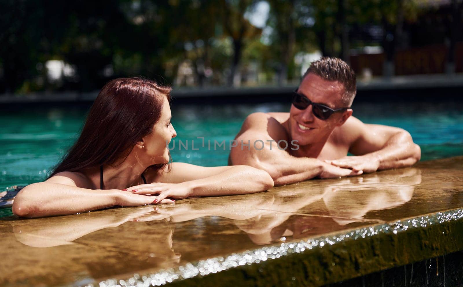 Positive people. Cheerful couple or friends together in swimming pool at vacation by Standret