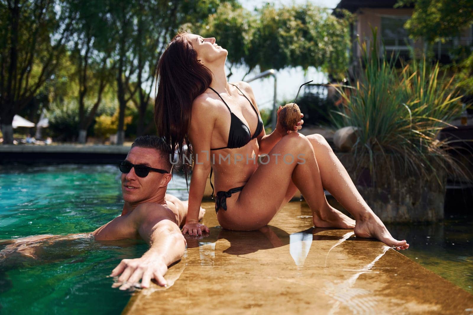 Positive people. Cheerful couple or friends together in swimming pool at vacation by Standret