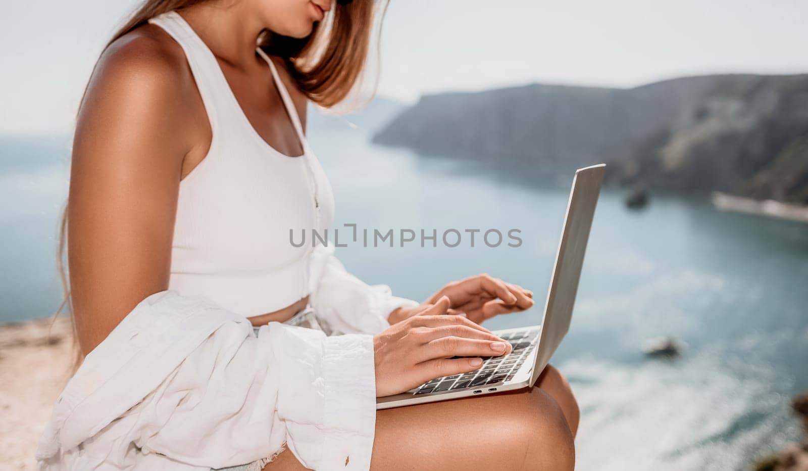 Woman sea laptop. Business woman in yellow hat freelancer with laptop working over blue sea beach. Girl relieves stress from work. Freelance, digital nomad, travel and holidays concept by panophotograph