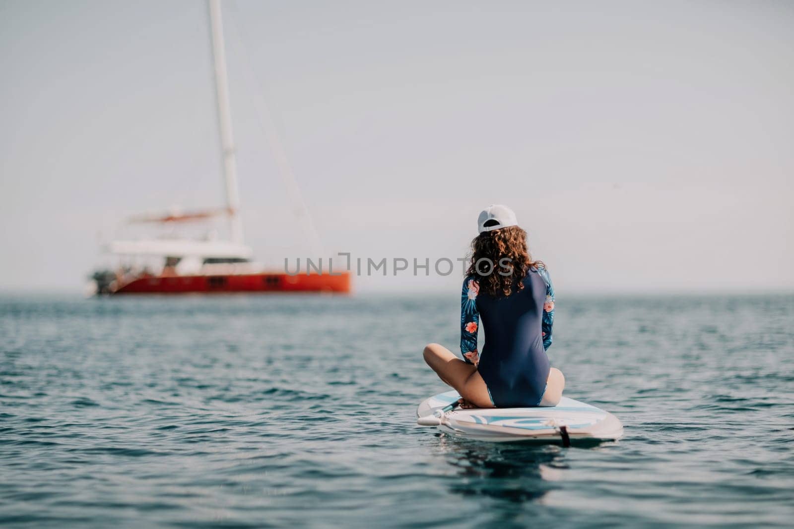 Woman sup yoga. Middle age sporty woman practising yoga pilates on paddle sup surfboard. Female stretching doing workout on sea water. Modern individual hipster outdoor summer sport activity