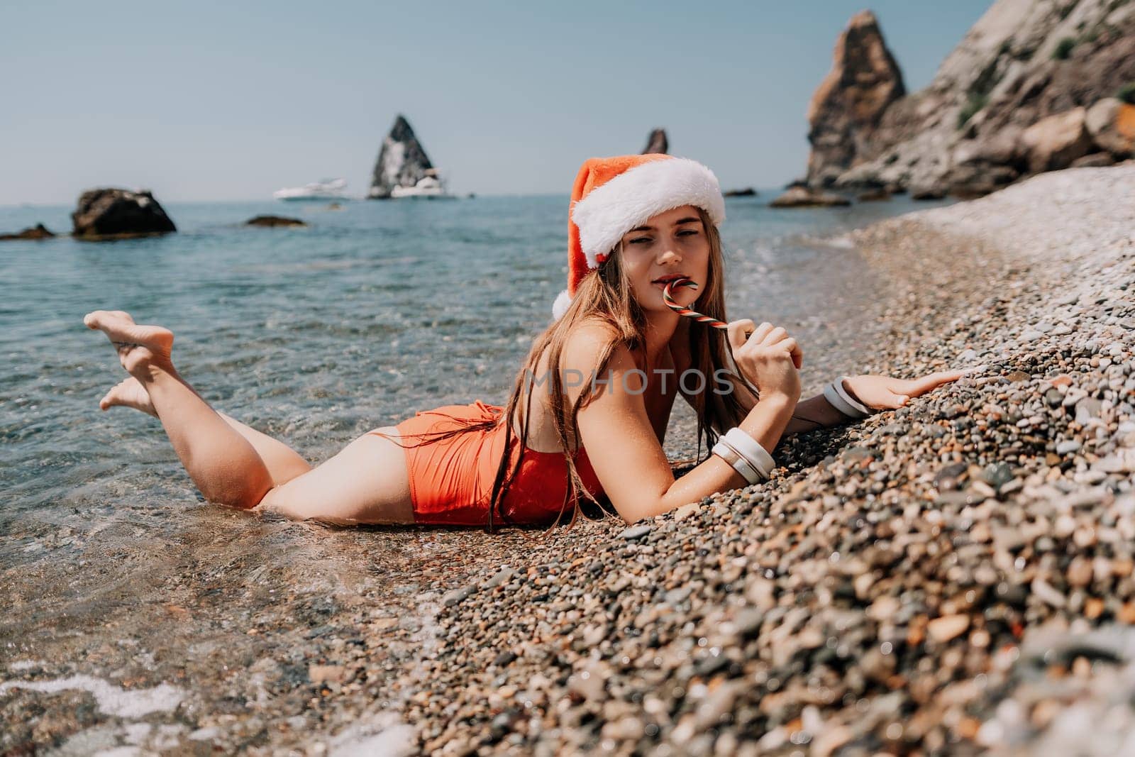 Woman travel sea. Happy tourist enjoy taking picture on the beach for memories. Woman traveler in Santa hat looks at camera on the sea bay, sharing travel adventure journey by panophotograph