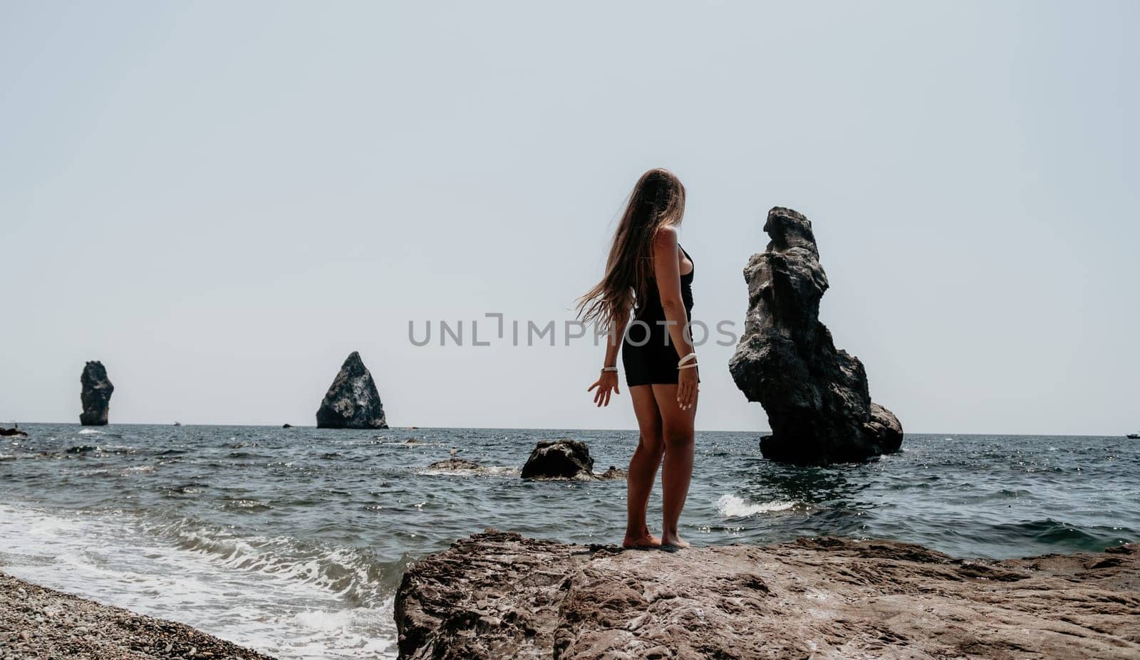 Woman summer travel sea. Happy tourist in hat enjoy taking picture outdoors for memories. Woman traveler posing on the beach at sea surrounded by volcanic mountains, sharing travel adventure journey by panophotograph