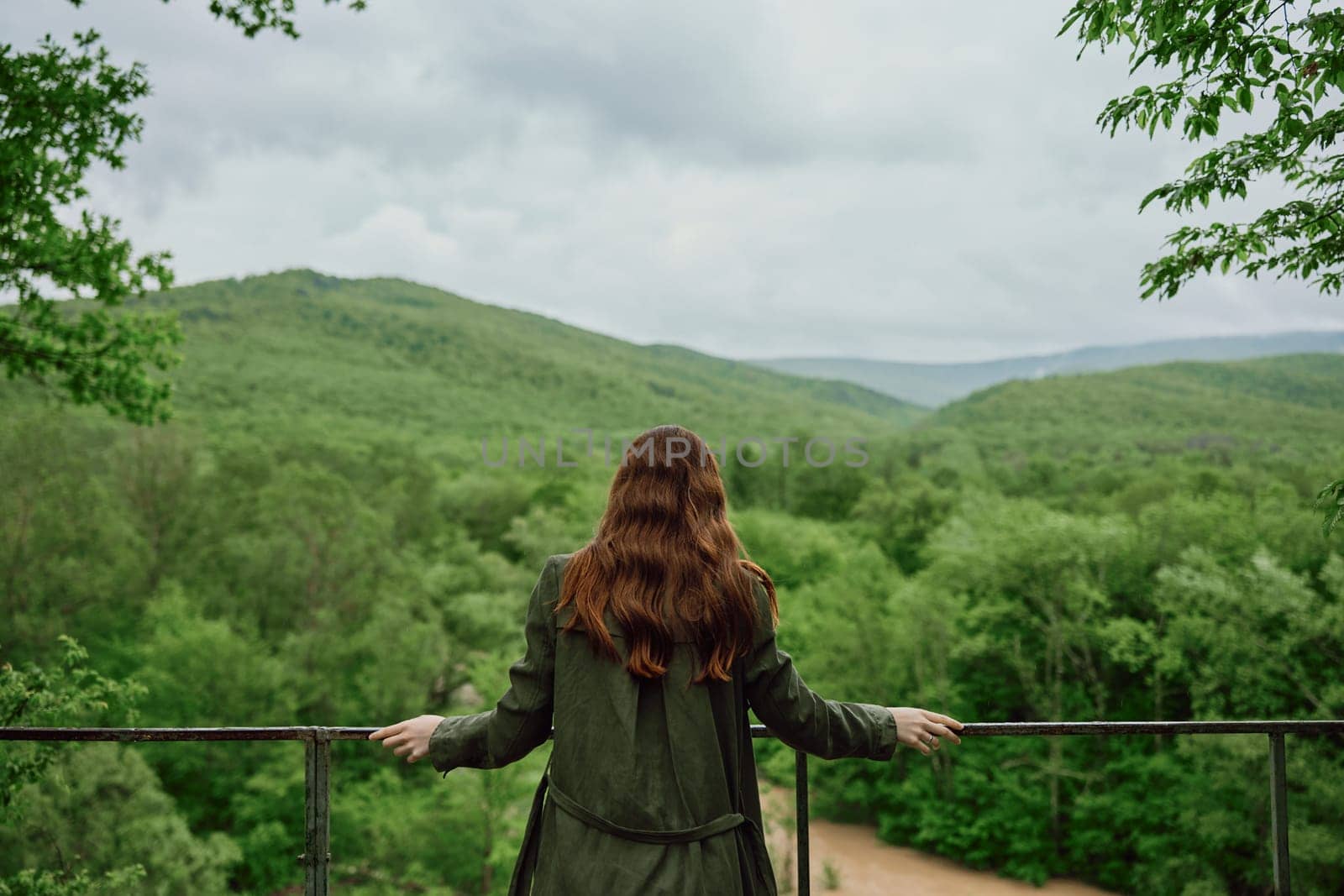 a red-haired woman with beautiful, well-groomed, long hair stands with her back to the camera and enjoys the view of the forest by Vichizh
