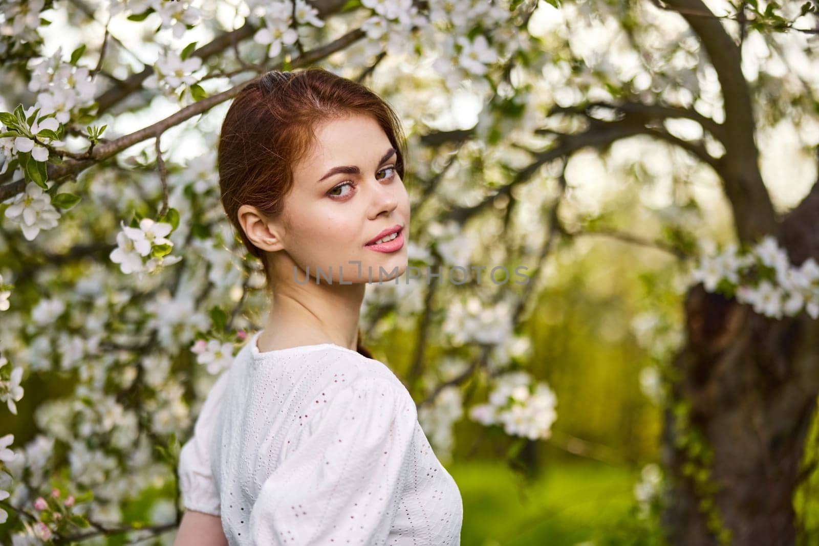 beautiful woman standing near blossoming bush by Vichizh