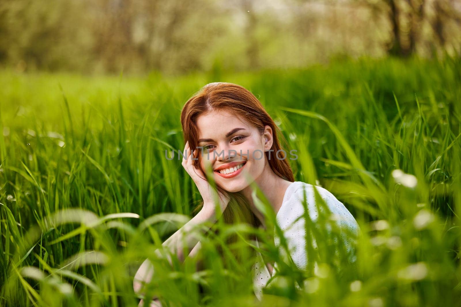 happy smiling redhead woman resting sitting in tall grass. High quality photo