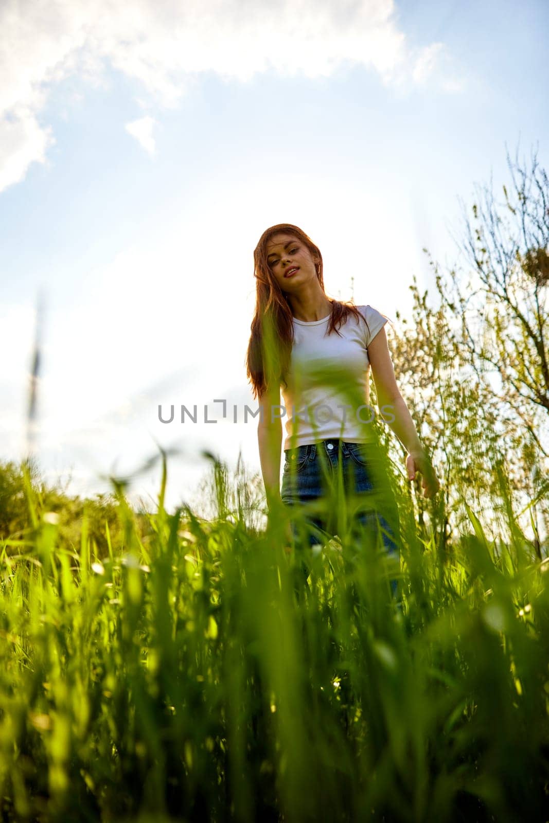 joyful woman posing in tall grass on a sunny day by Vichizh