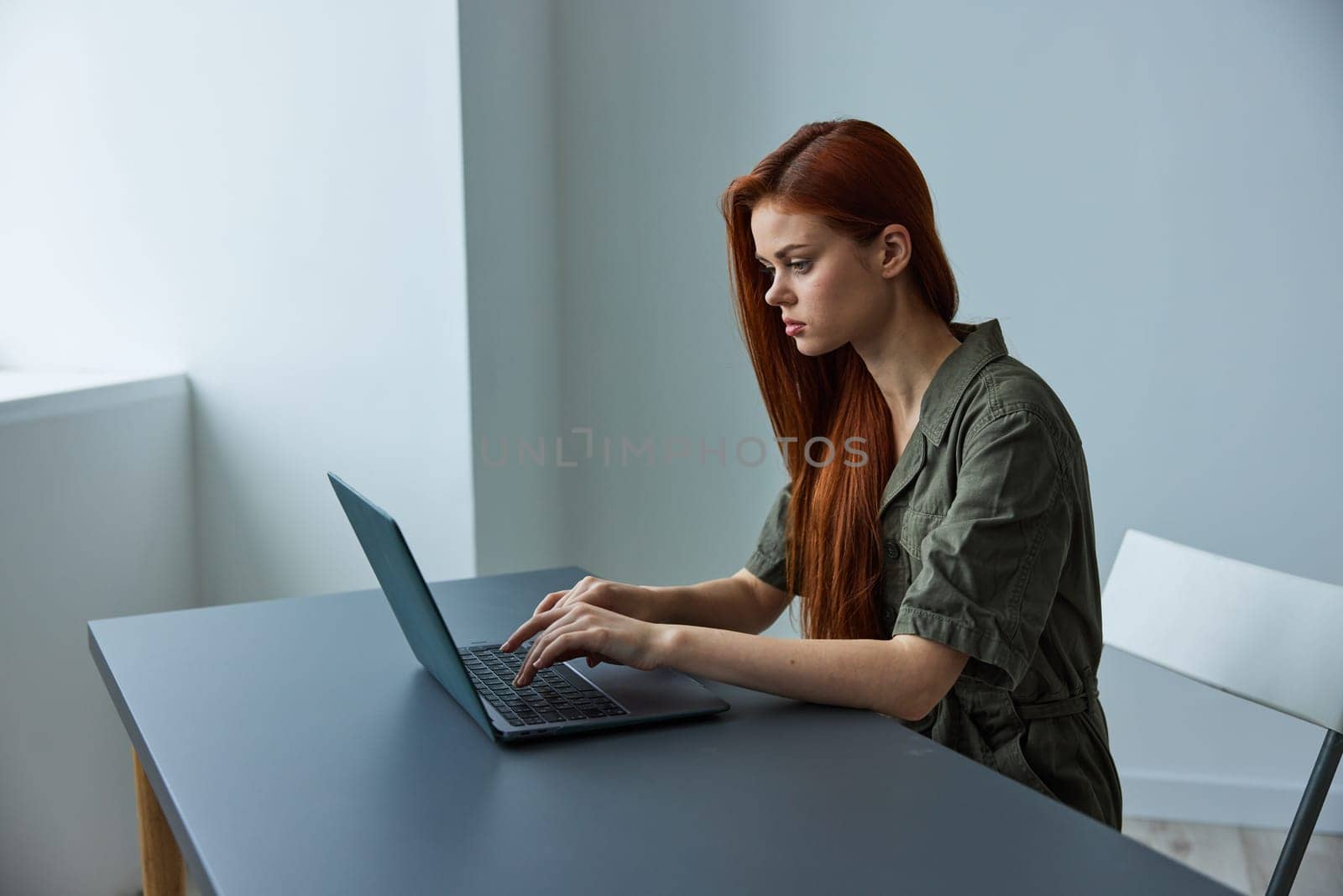 woman in bright office typing puzzled at laptop while working full time. High quality photo