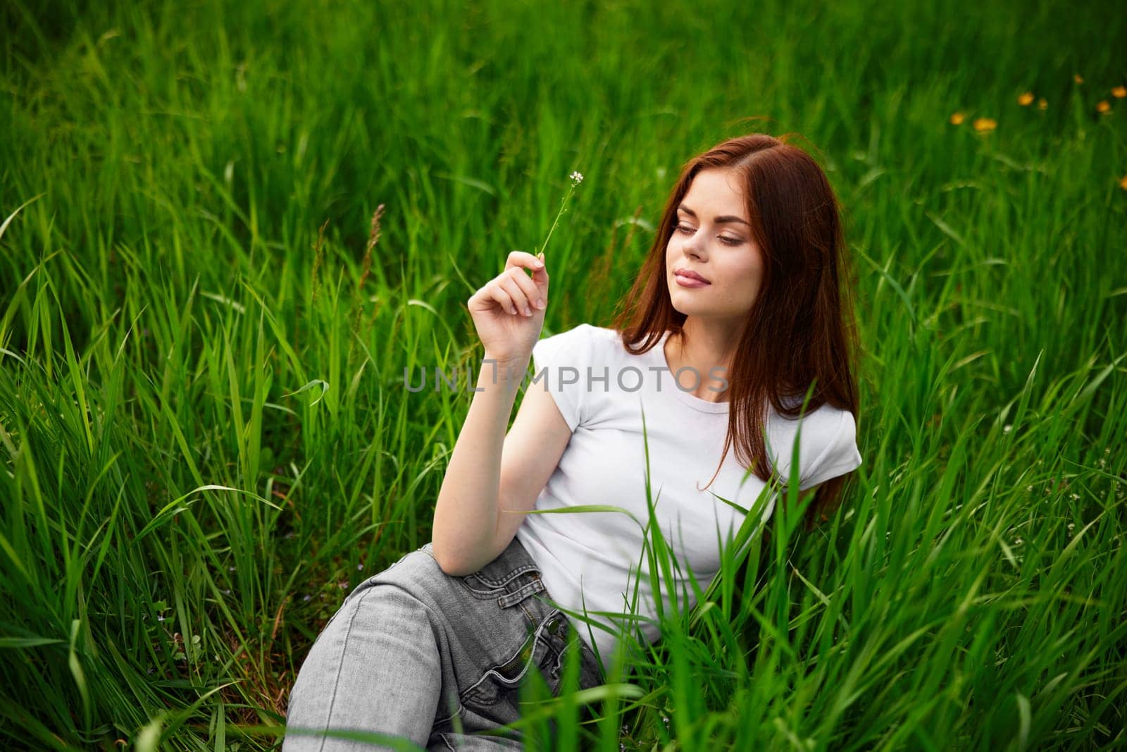 woman in gray jeans resting lying in the grass. High quality photo