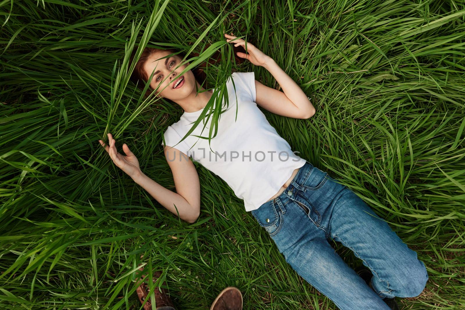 happy woman lies in tall grass covering her face with leaves. High quality photo