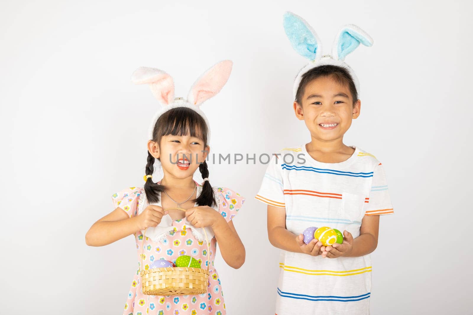 Happy Easter Day. Two smile Asian little girl and boy wearing easter bunny ears holding basket with eggs isolated on white background with copy space, Happy family children in holiday