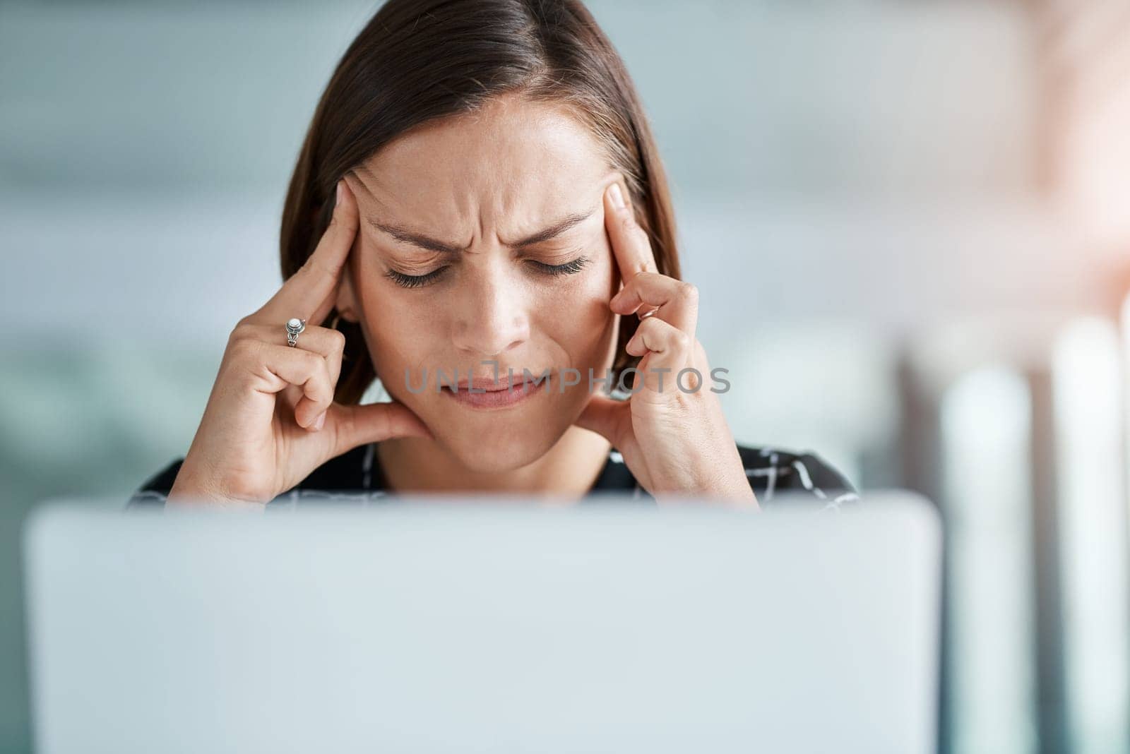 This headache is only getting worse. a young businesswoman suffering with a headache while working in an office. by YuriArcurs