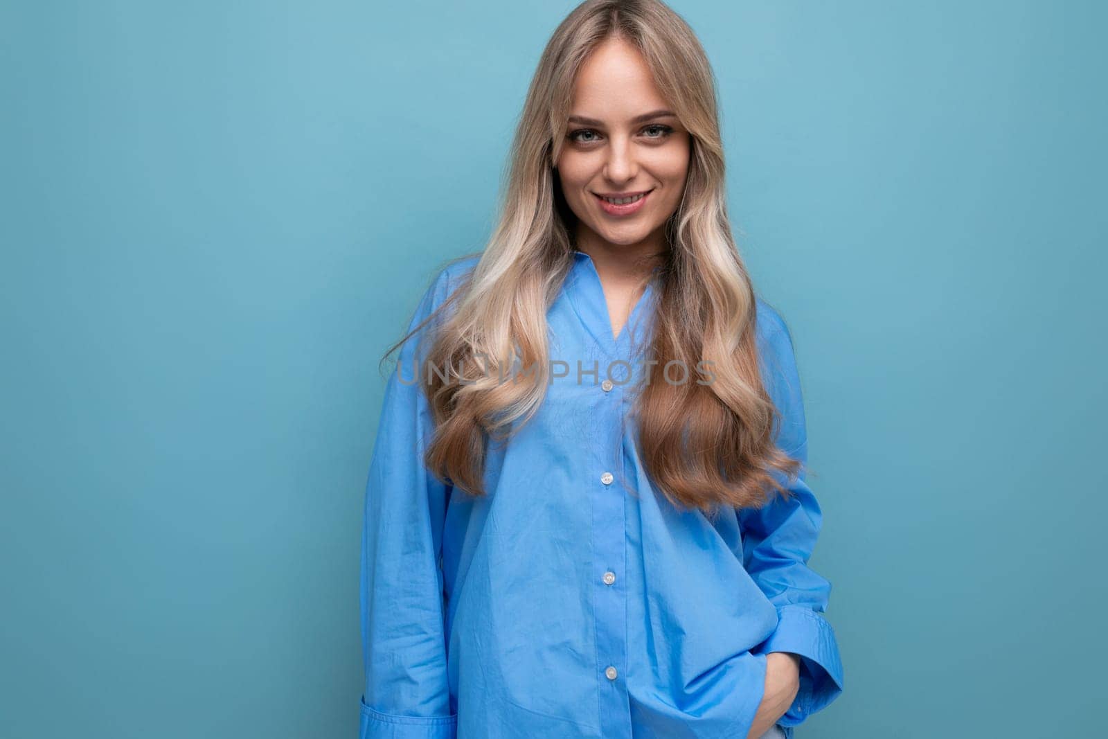 cheerful blond girl in a blue shirt isolated on a blue background by TRMK