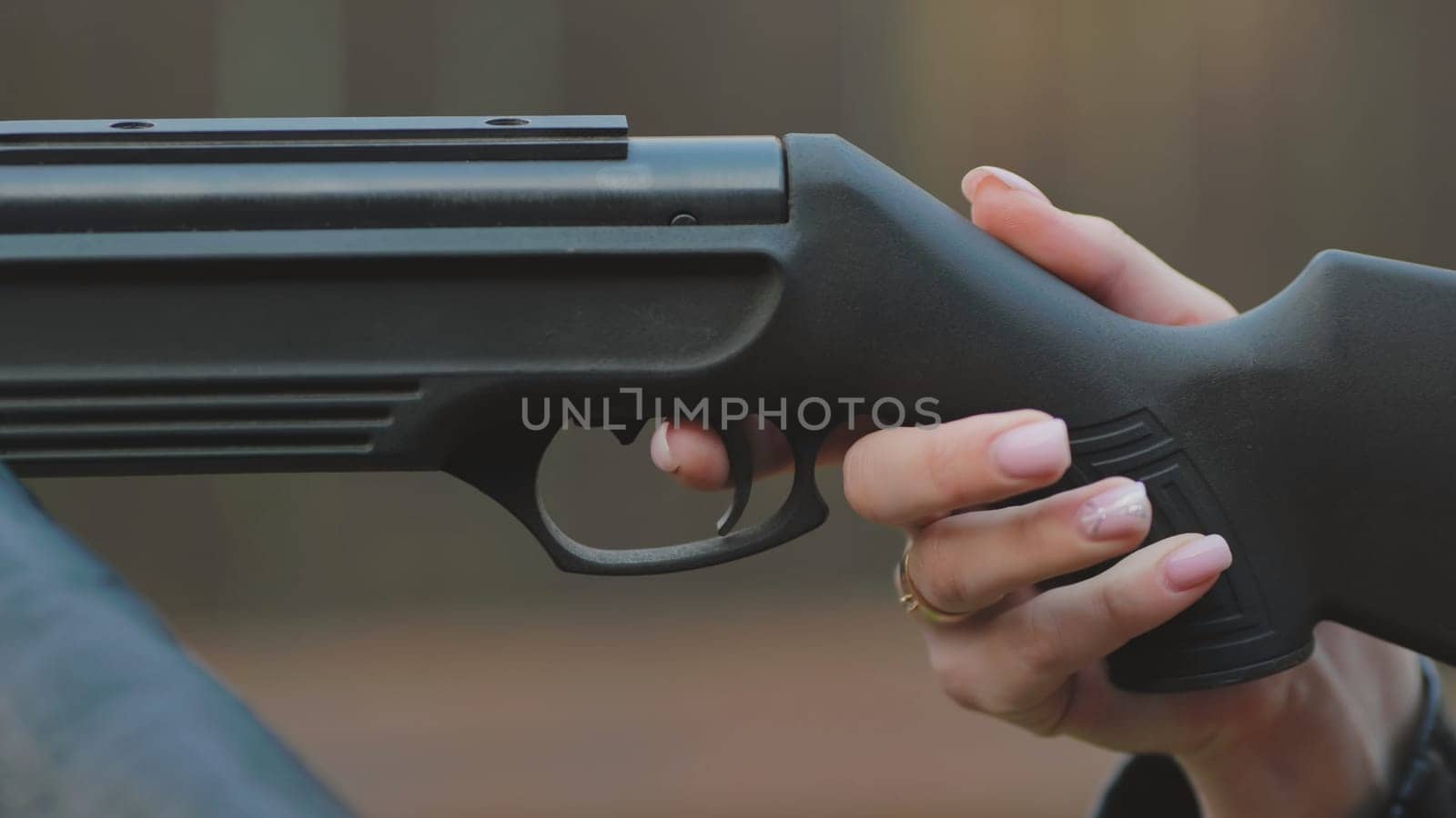 The girl is shooting from an air gun. Close-up of her hands