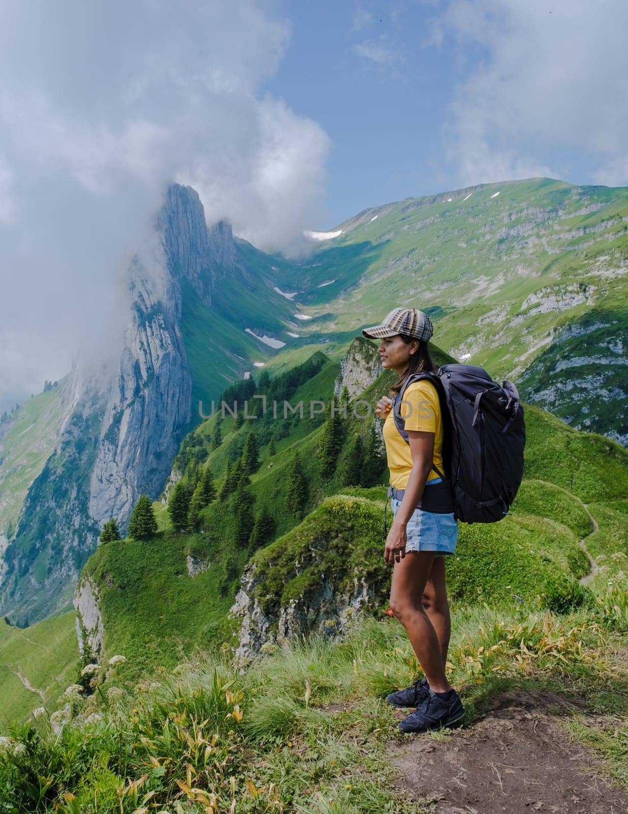 women hiking in the Swiss Alps mountains at summer vacation with a backpack and hiking boots by fokkebok