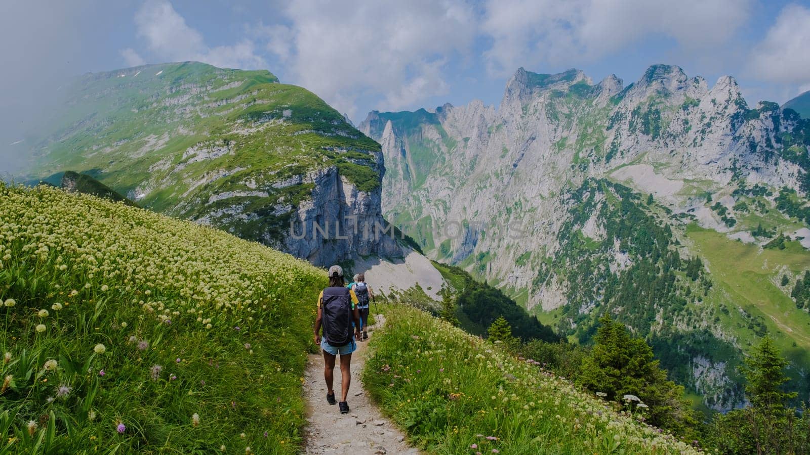Asian women hiking in the Swiss Alps mountains at summer vacation with a backpack and hiking boots by fokkebok