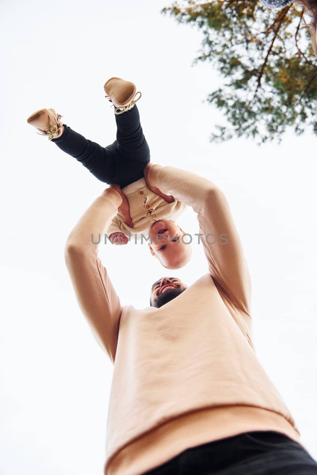 Bearded father playing with his child outdoors at sunny daytime outdoors.