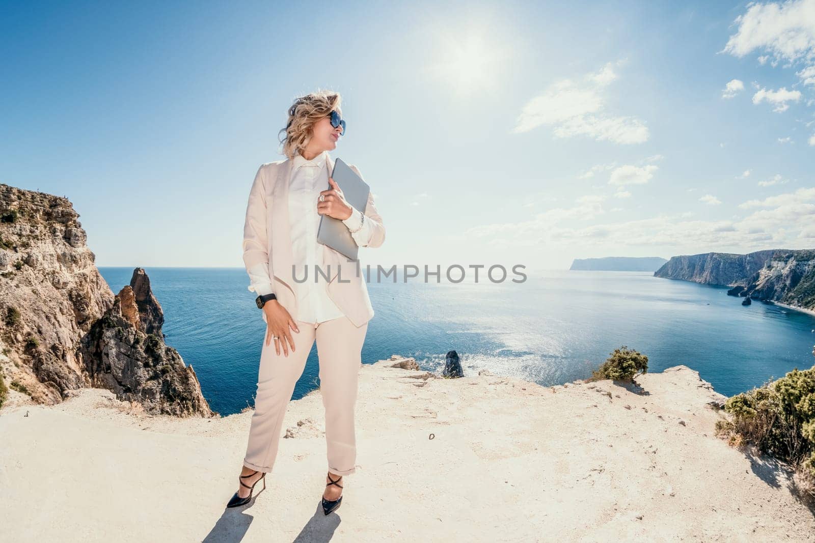 Digital nomad, Business woman working on laptop by the sea. Pretty lady typing on computer by the sea at sunset, makes a business transaction online from a distance. Freelance, remote work on vacation by panophotograph