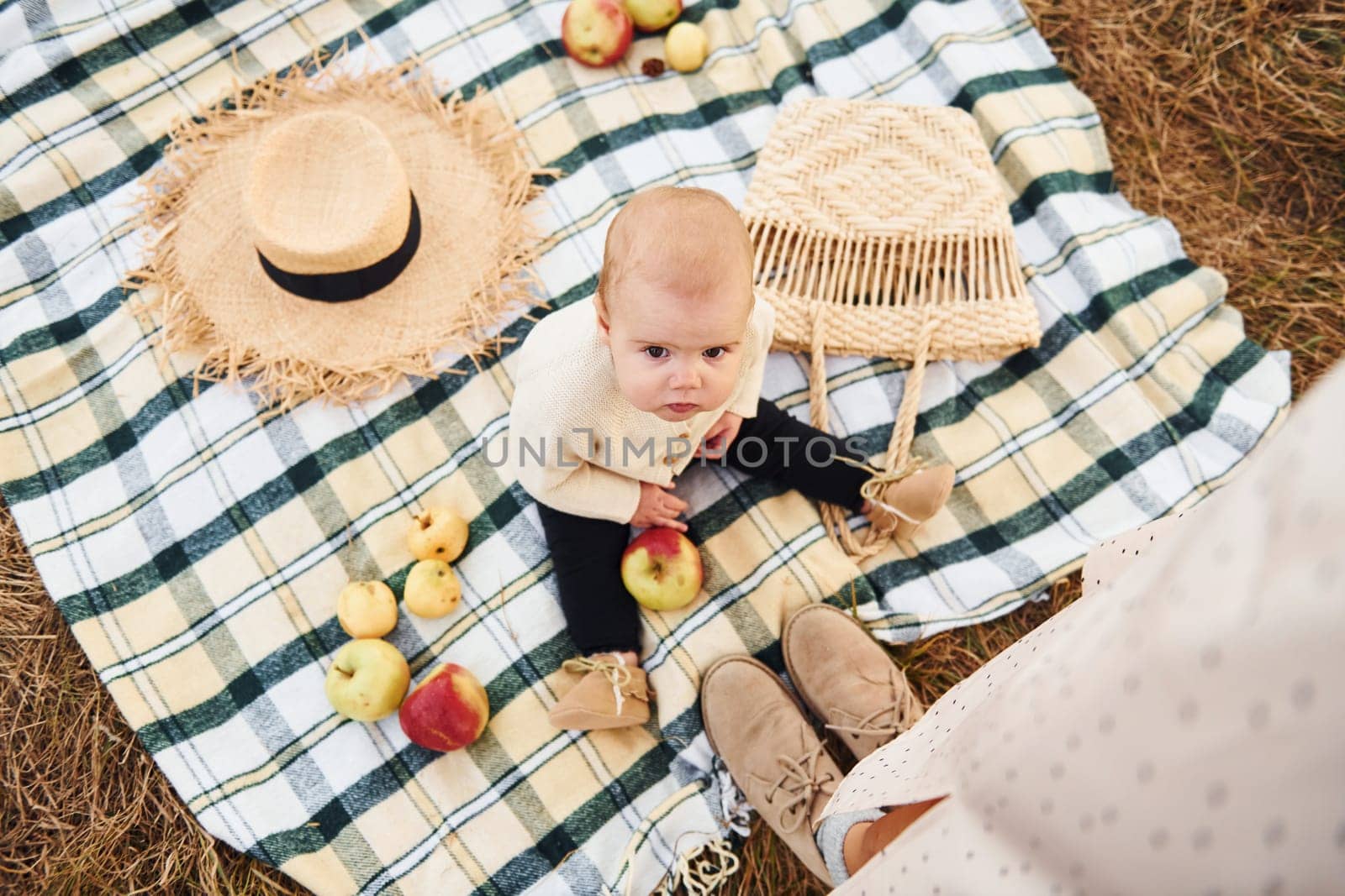 Top view. Having picnic. Young mother with her little baby rests outdoors at autumn season.