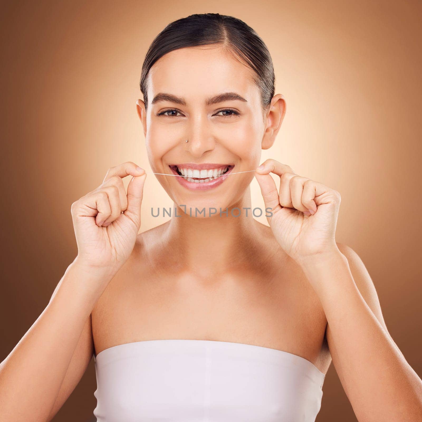 Dental, floss and happy woman cleaning teeth for oral hygiene routine, self care flossing or tooth healthcare. Mouth plaque treatment, face portrait smile and studio female beauty on brown background by YuriArcurs